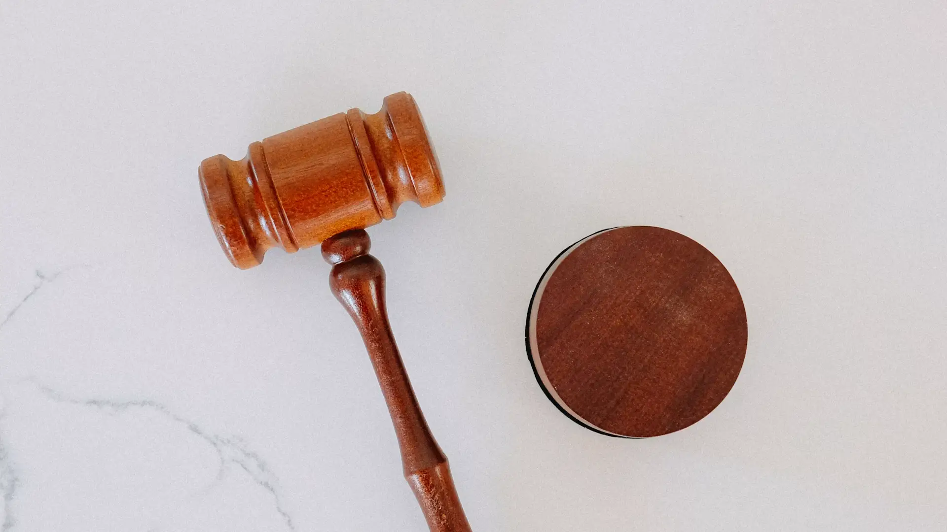 A wooden judges gavel on a marble table top.
