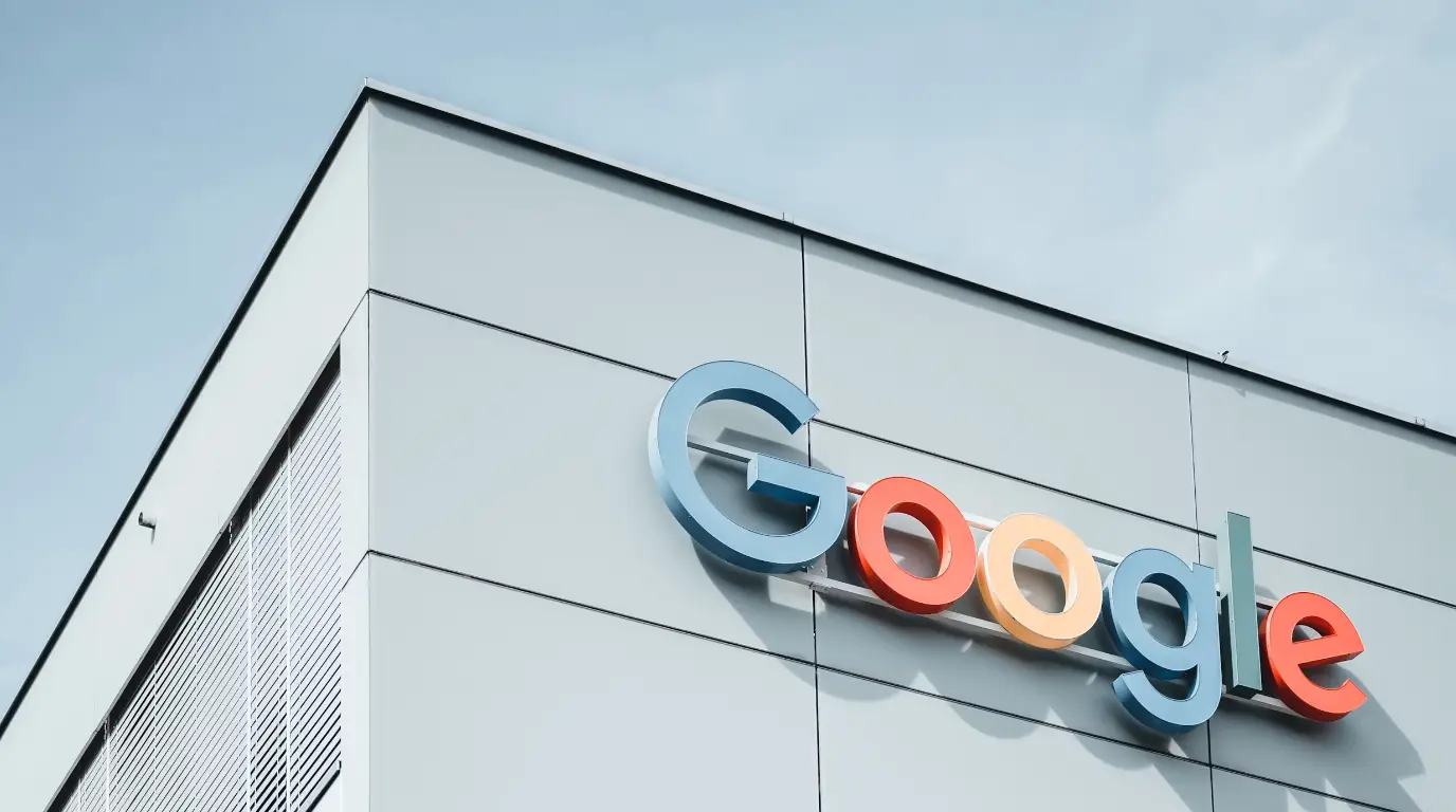 A modern building against a blue sky with a Google sign hanging from the top corner.