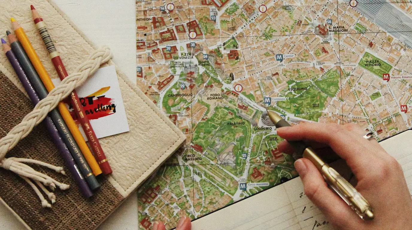 A colorful paper map with pencils and a hand writing in pen.